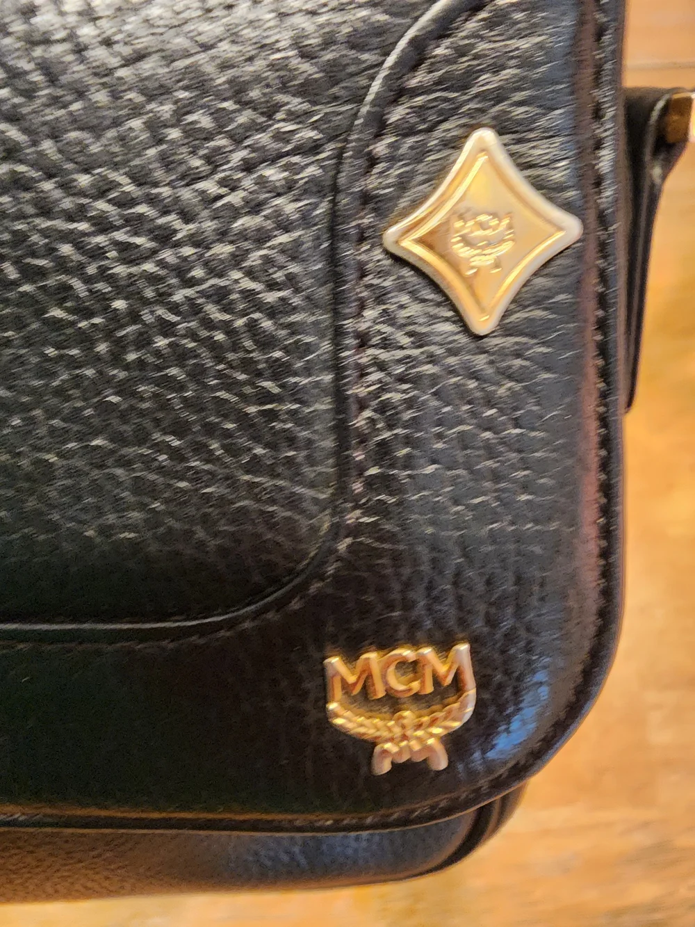 vintage MCM black pebbled leather studded crossbody bag featuring a front plaque